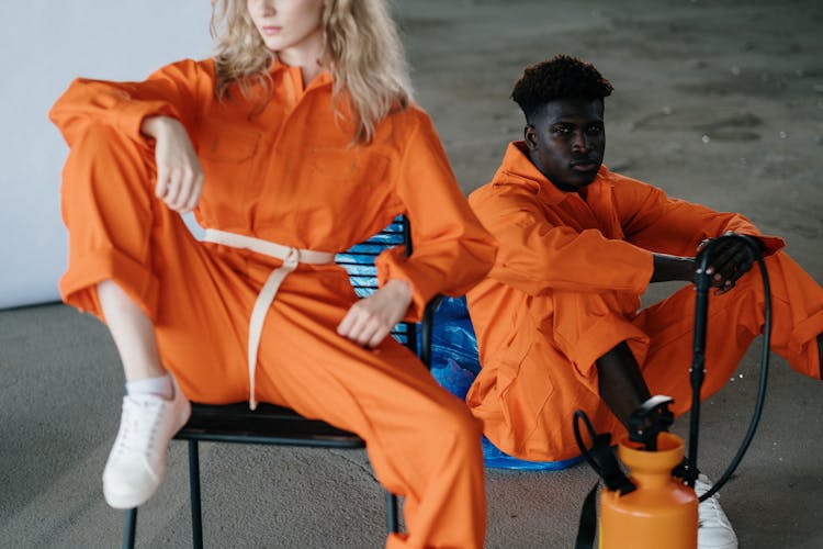 A Man And Woman In Orange Jumpsuit Sitting