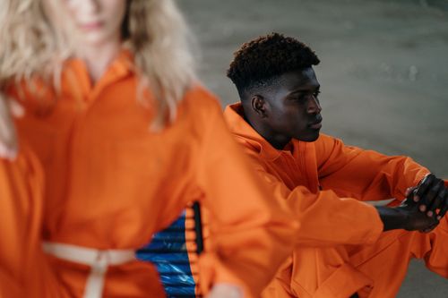 Free A contemplative man in orange clothing sitting indoors with focus and seriousness. Stock Photo