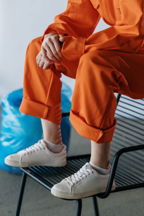 Free Close-up of a person in an orange uniform sitting on a black chair indoors. Stock Photo