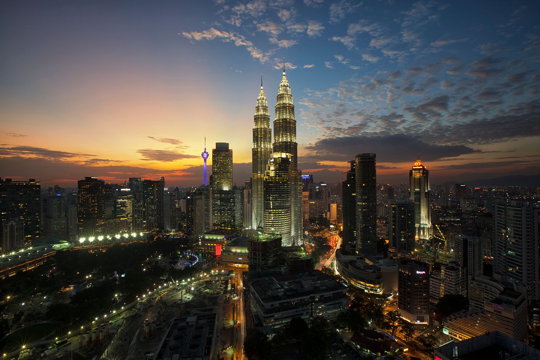 Discover the iconic Kuala Lumpur skyline with the Petronas Towers at twilight, showcasing the vibrant city lights.
