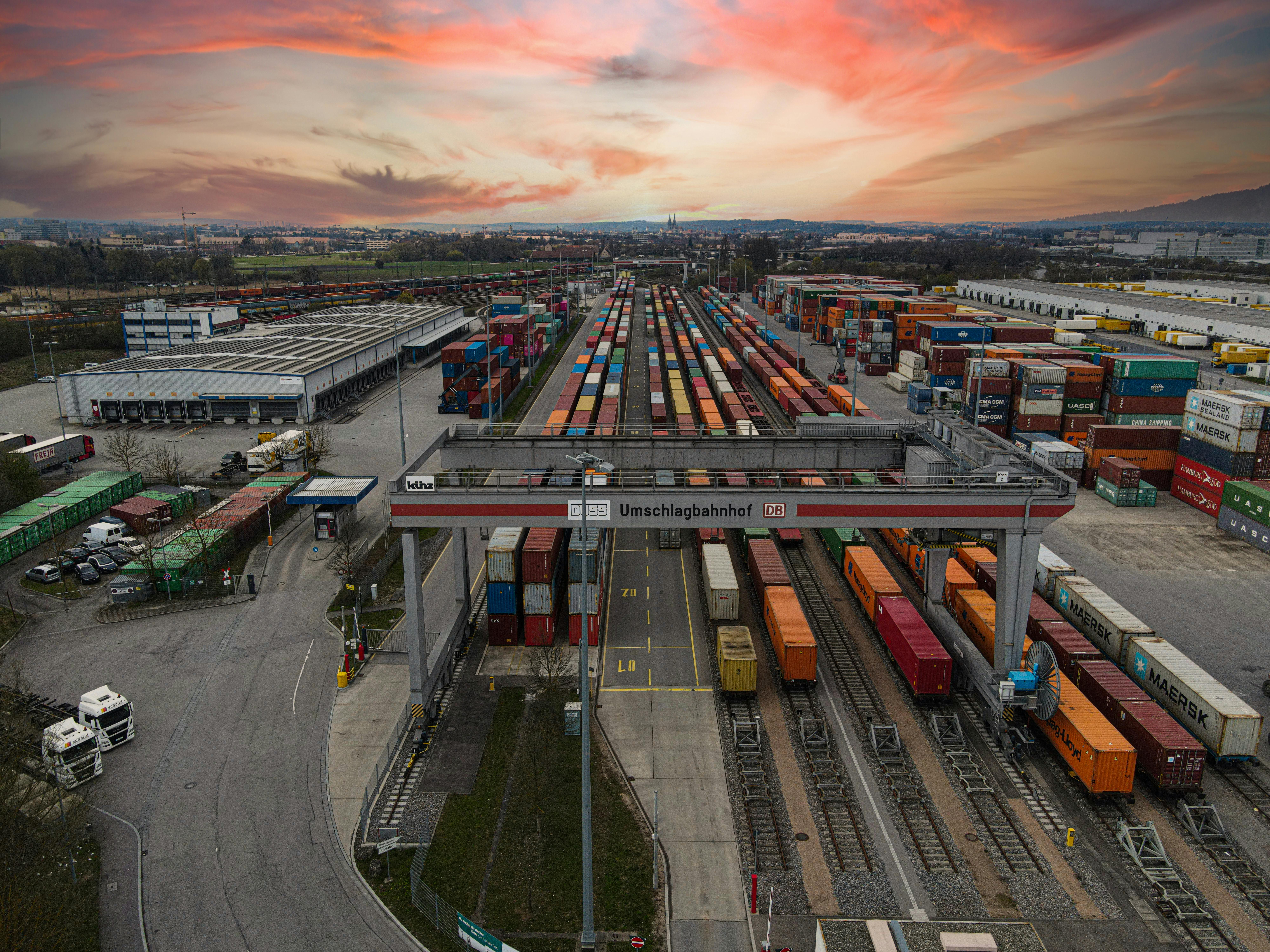 Aerial view of a bustling shipping yard with colorful containers at sunset, highlighting logistics.