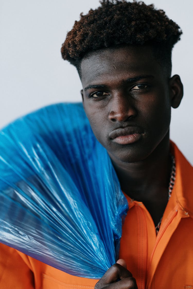 Man In Orange Polo Shirt Holding Blue Plastic Bag