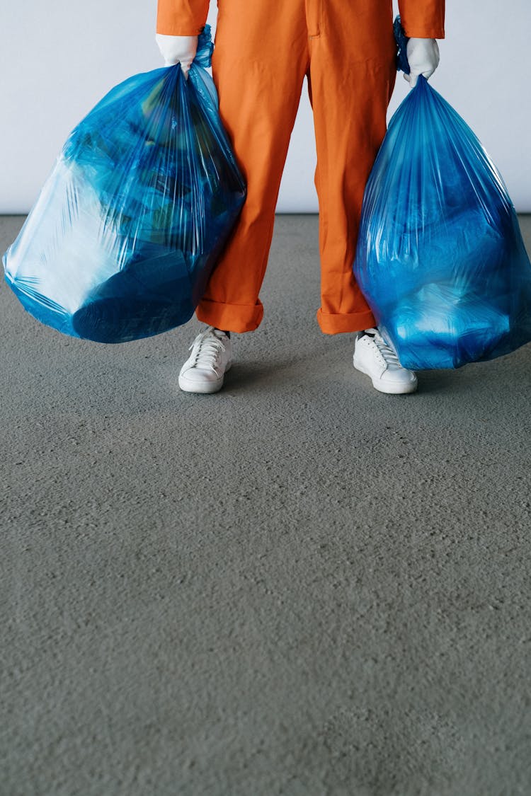 Hands Holding Blue Garbage Bags