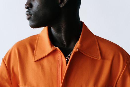 Close-up portrait of a man wearing a vibrant orange jacket against a neutral background.