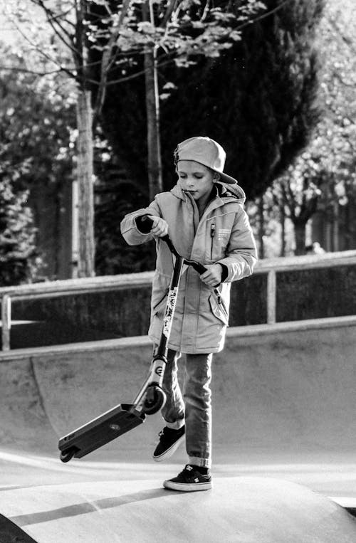 Free Grayscale Photo of Kid Holding a Scooter Stock Photo