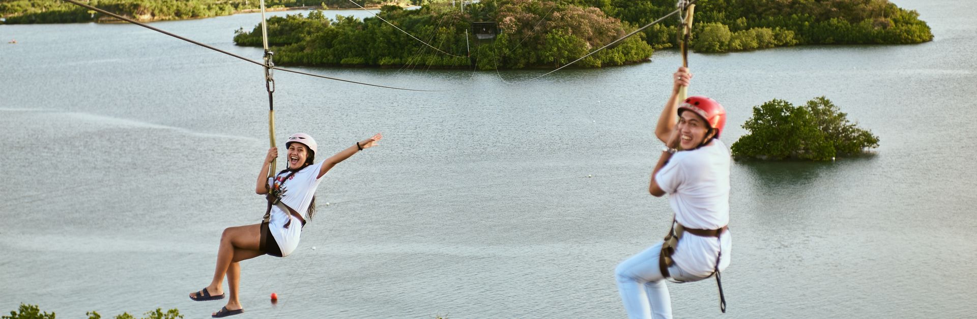 Two women enjoying a thrilling zipline ride over a beautiful river landscape.