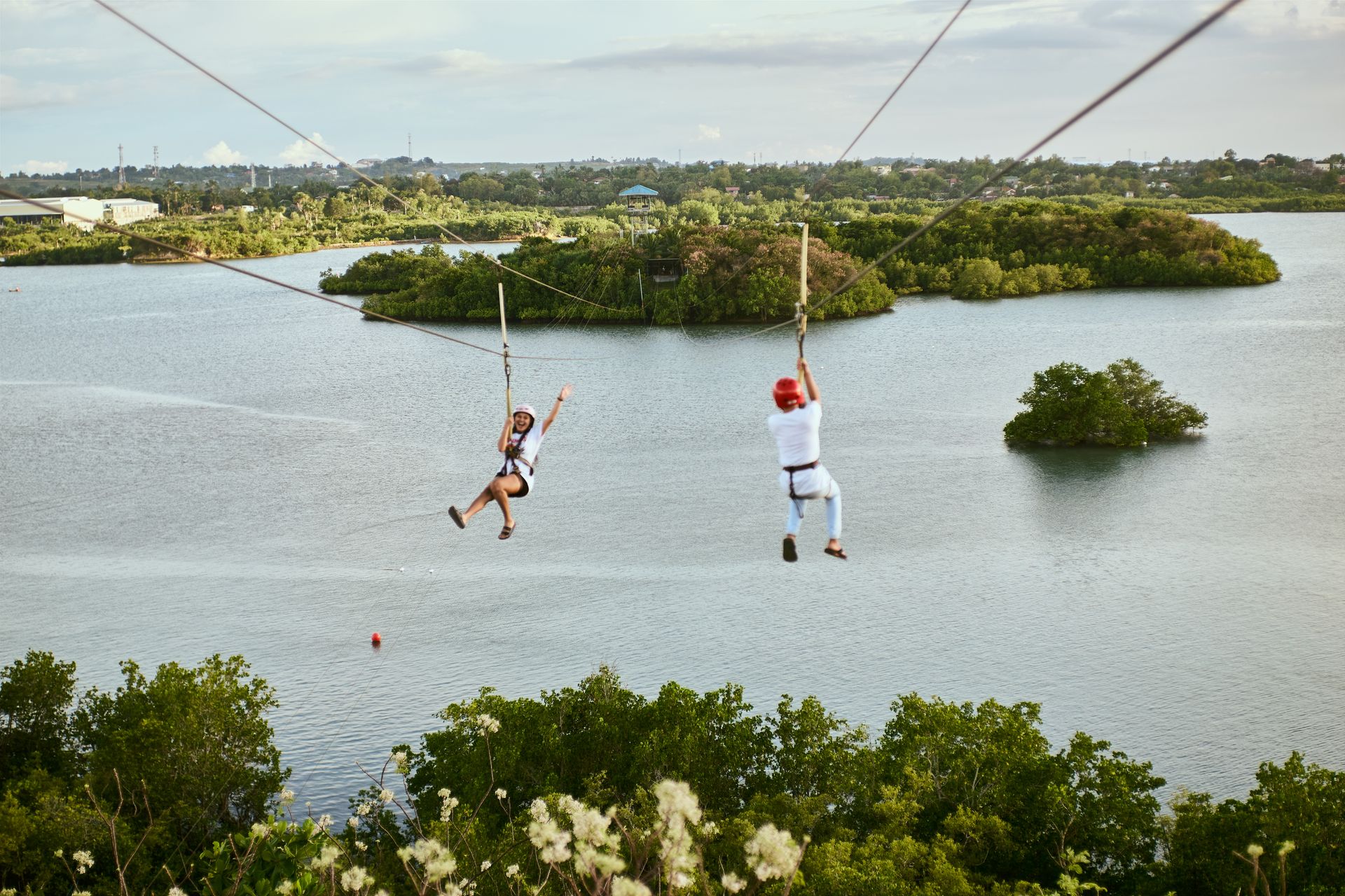 Enjoy a thrilling zipline ride over a scenic water landscape, surrounded by lush greenery.