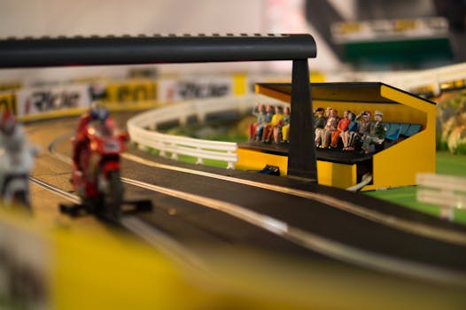 Close-up of model motorcycle racing on a miniature track with detailed spectator stand.