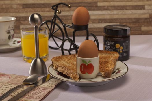 A cozy breakfast setup featuring eggs and toast with a bicycle holder and orange juice for a warm start to the day.