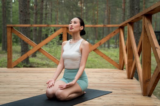 Asian woman meditating peacefully on a yoga mat outdoors, embodying tranquility and focus.