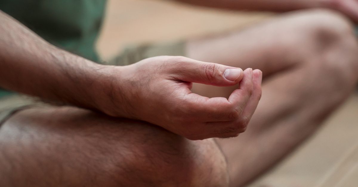 Close-up of hands resting in a calm meditation mudra on crossed legs
