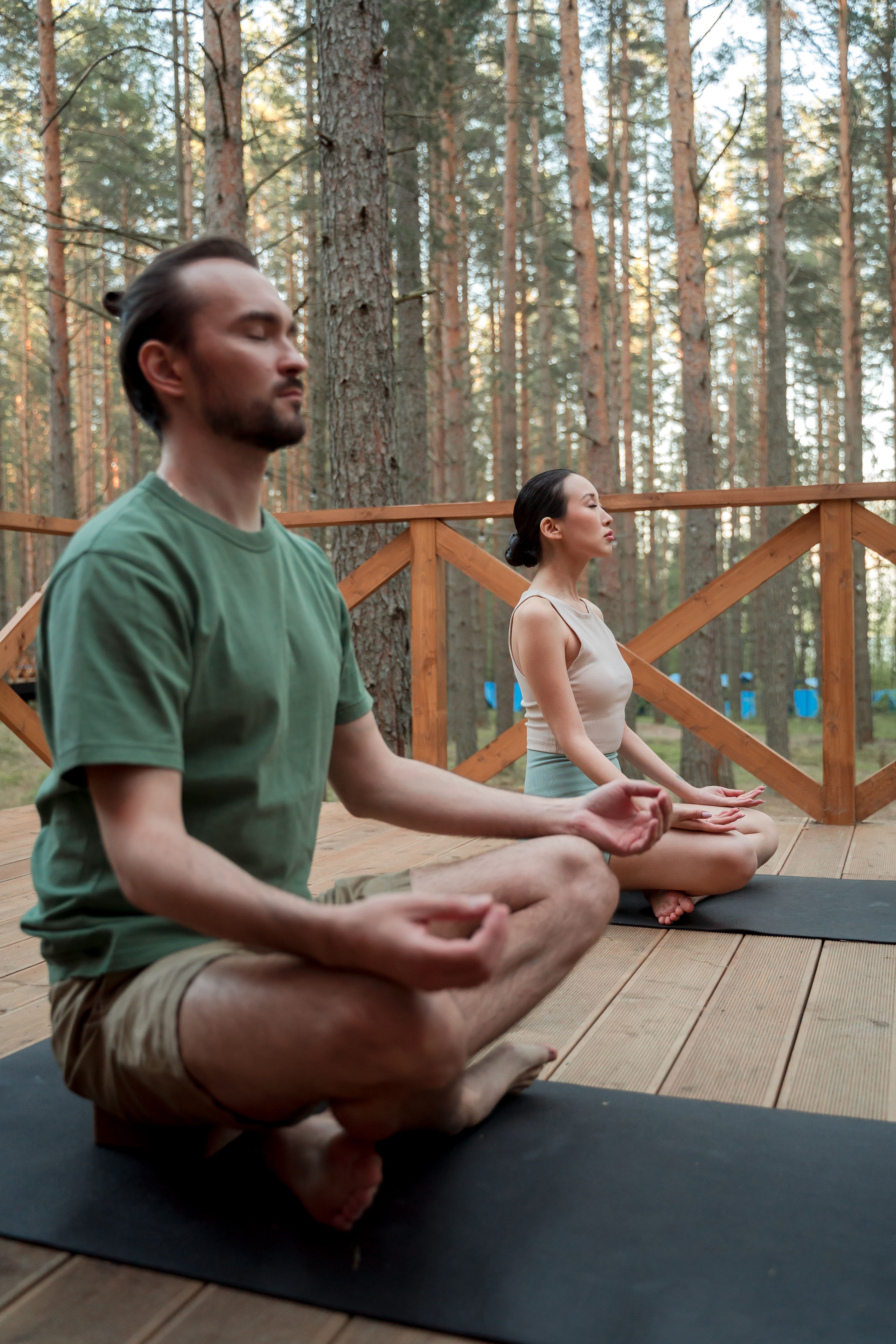 A couple practices outdoor yoga meditation for mindfulness and relaxation in the forest.