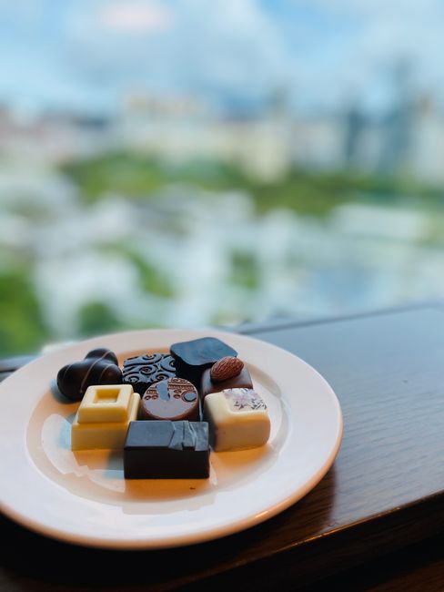 A box of filled chocolates with several pieces cut in half, revealing caramel, hazelnut praline, and fruit cream centers inside glossy dark and milk chocolate shells.