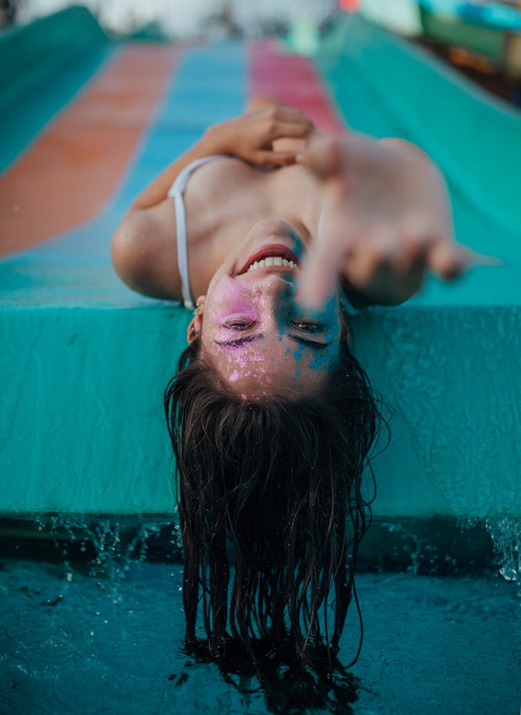 Woman With Colored Powder On Her Face Lying On The Swimming Pool Slide 