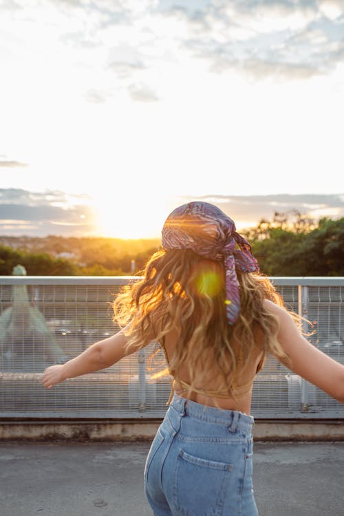 Woman in Blue Denim Jeans Standing Near Metal Fence