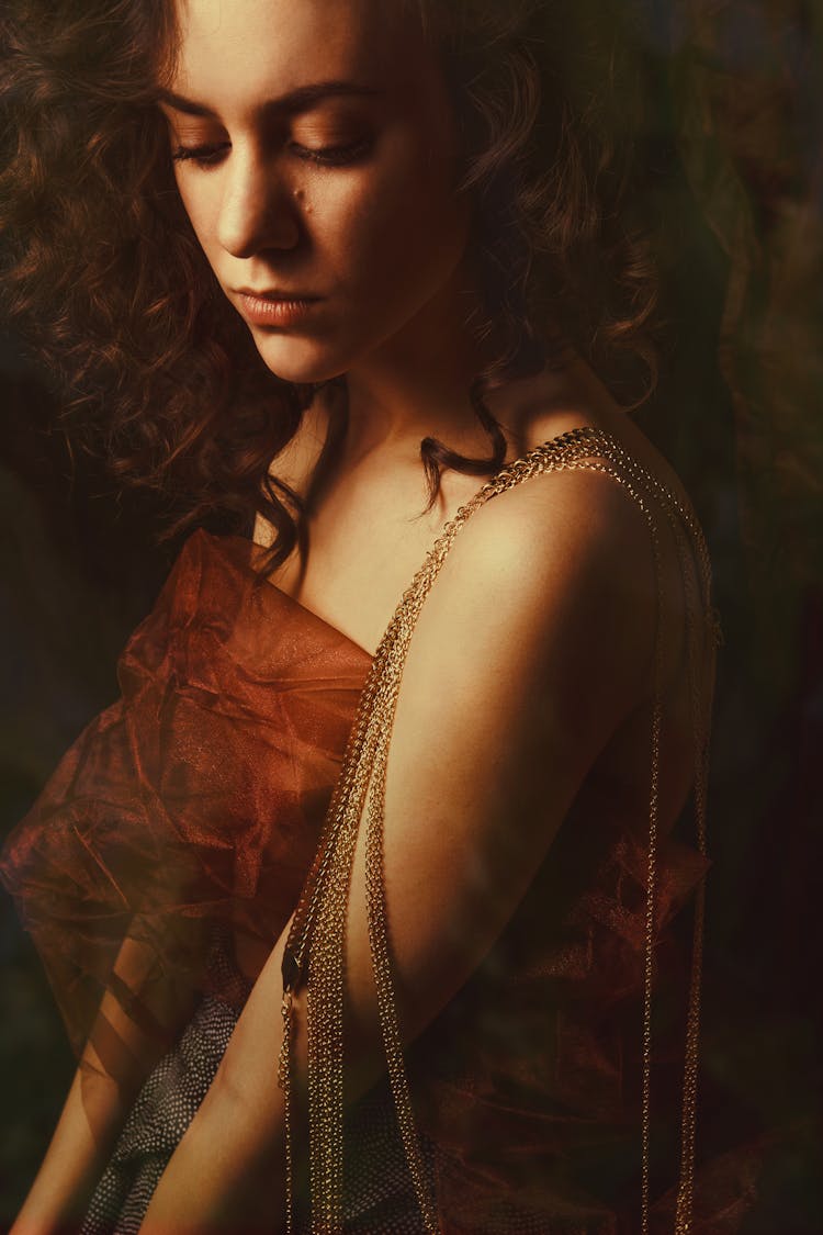 A Woman In Brown Sheer Top With Chains Over Her Shoulder
