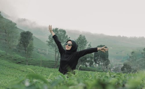 Free A woman in a hijab enjoys the misty green landscape of West Sumatra, Indonesia, expressing freedom and happiness. Stock Photo