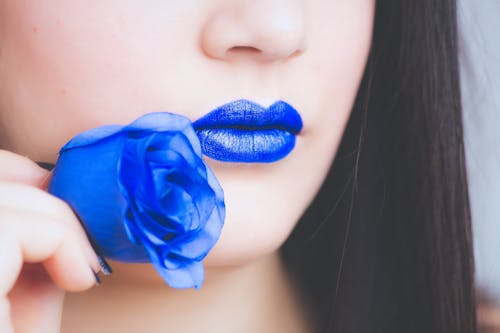 拿著藍色玫瑰花的藍色唇膏的女人