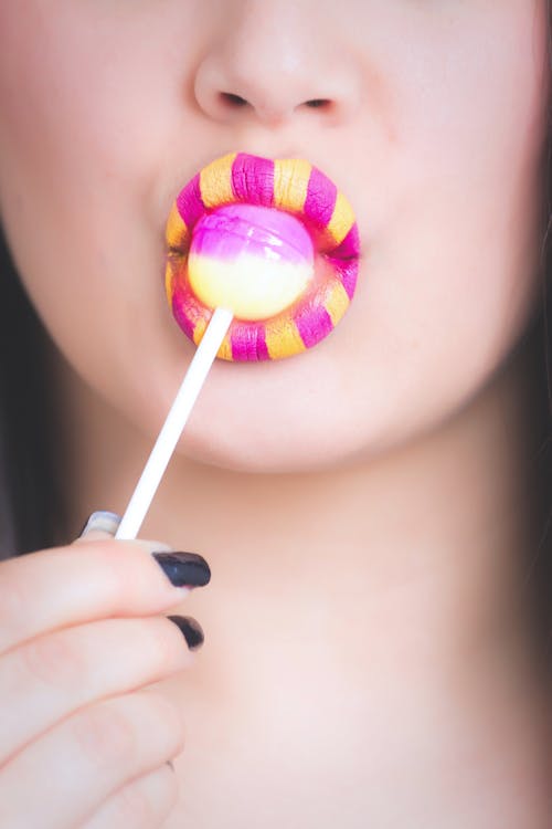 Woman Licking Pink and White Lollipop