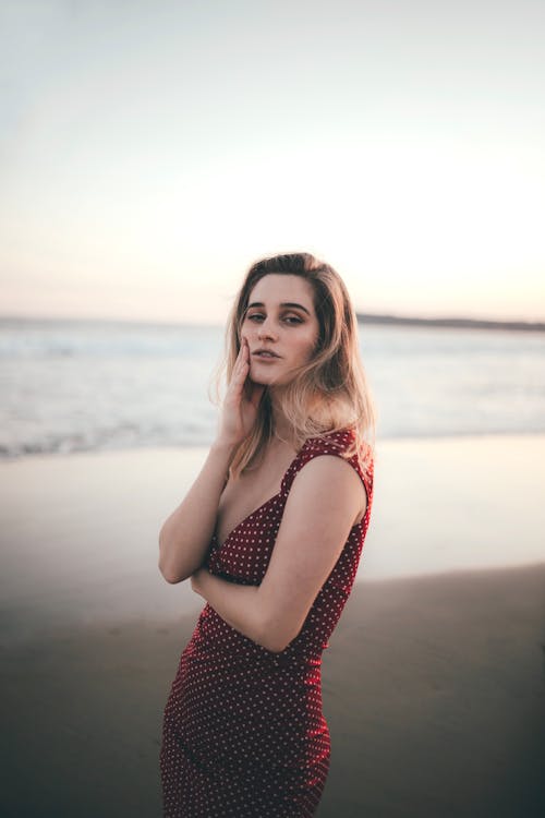 Woman in Red Polka Dot Dress Standing on Shore