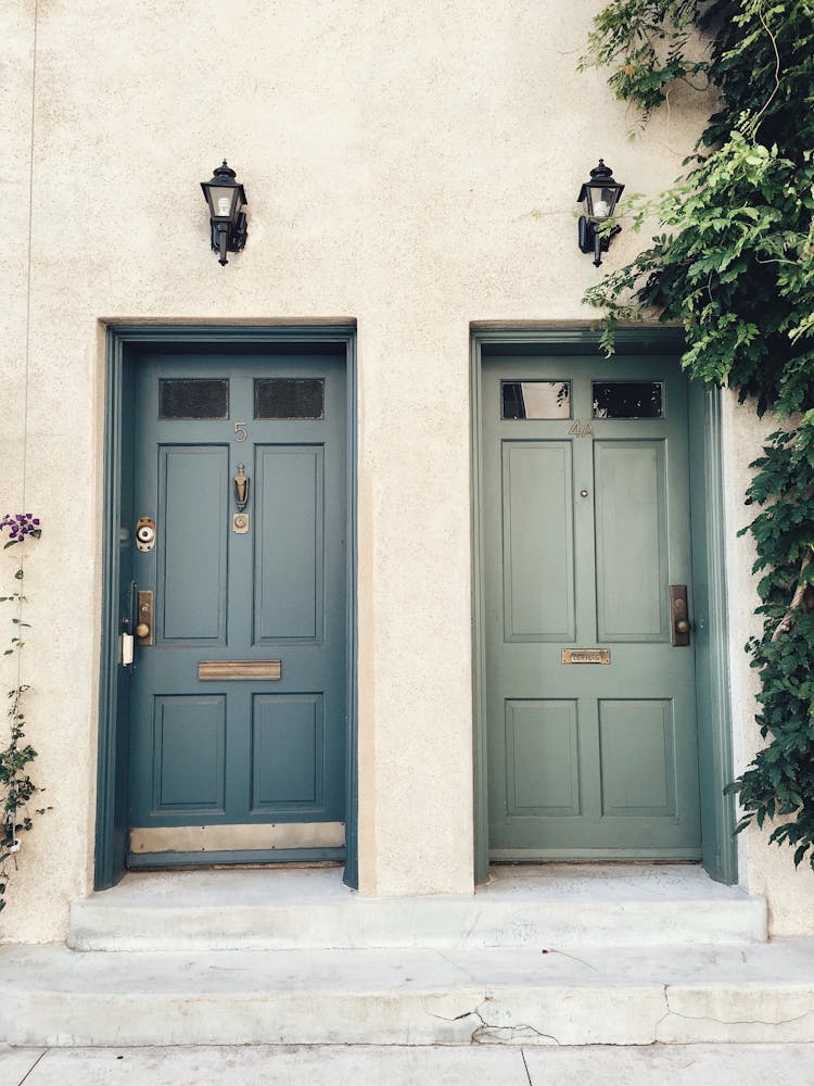 Two Adjacent Wooden Front Doors With Lampposts