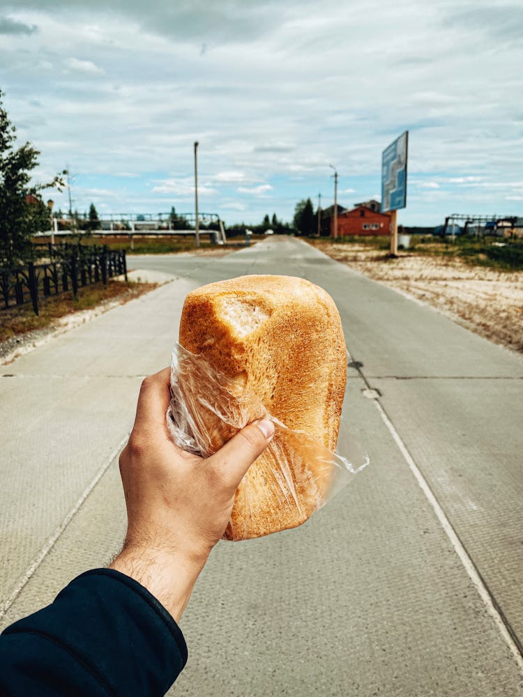 Hand Holding Loaf Bread In Clear Plastic