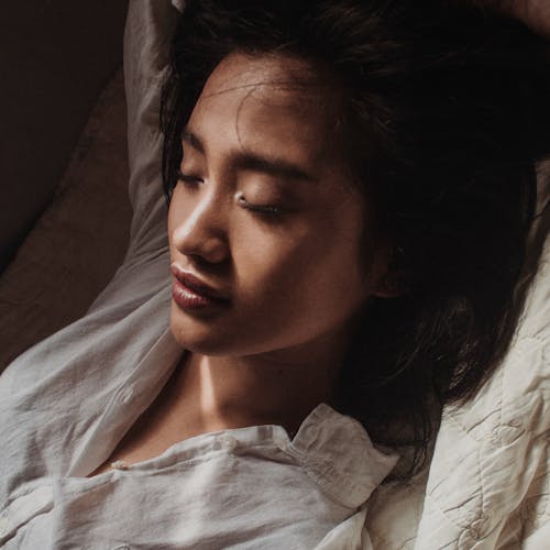 Woman in White Shirt Lying on Bed