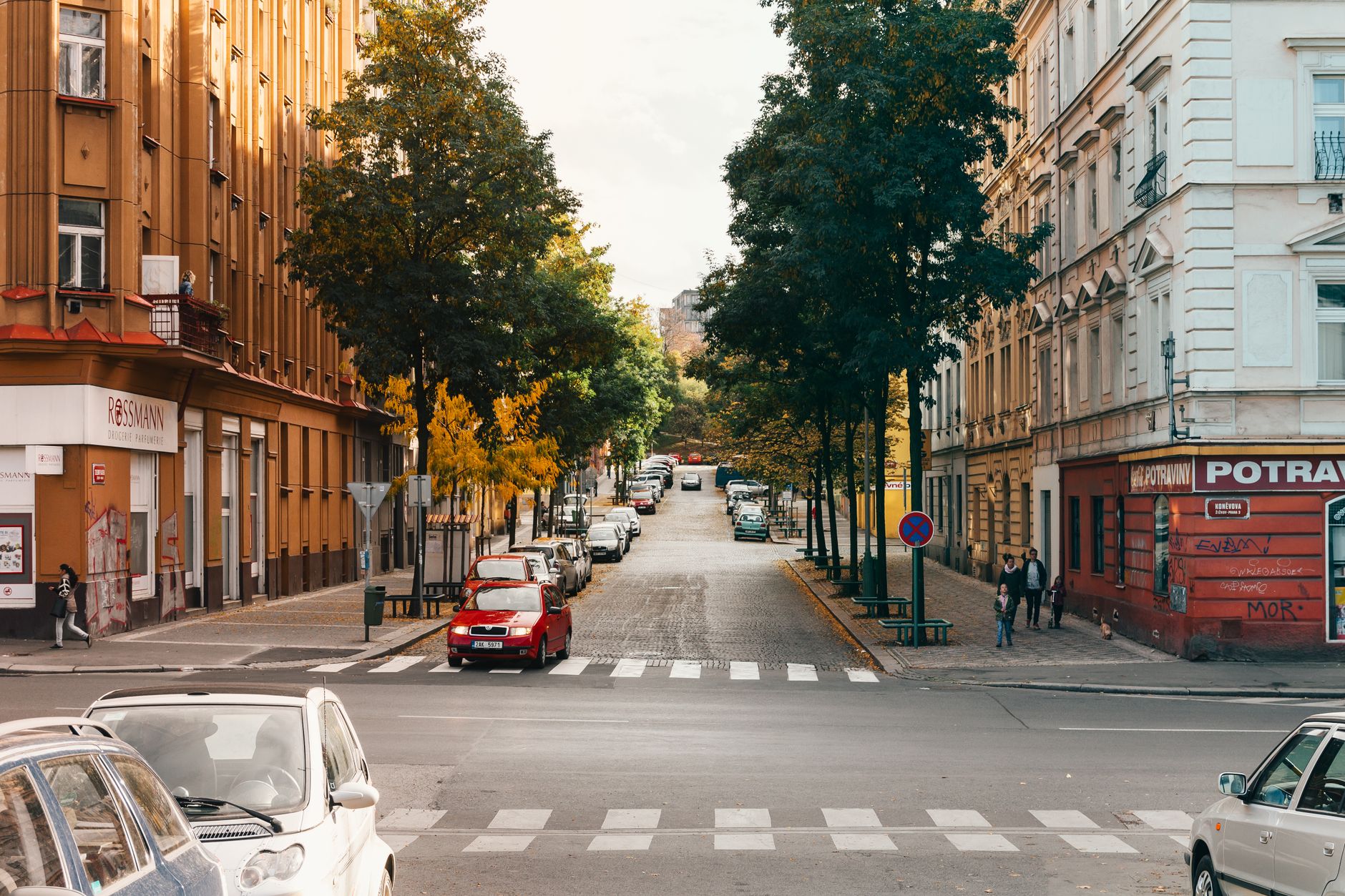 Explore a vibrant Prague street with classic architecture and autumn foliage.