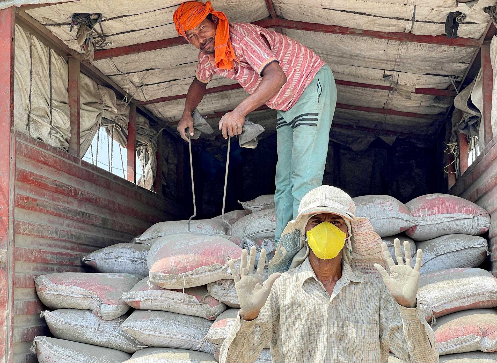 Workers unloading sacks from a truck in Sahibzada Ajit Singh Nagar, India, showcasing teamwork and labor.