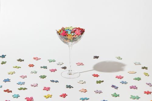 Free A unique still life photo of puzzle pieces in a cocktail glass on a white studio background. Stock Photo