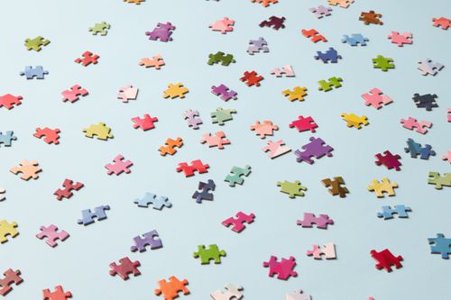Free Scattered colorful puzzle pieces on a light blue backdrop, perfect for jigsaw enthusiasts. Stock Photo