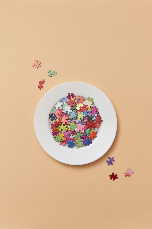 Free A ceramic plate filled with colorful puzzle pieces on a pastel background. Perfect for creative concepts. Stock Photo
