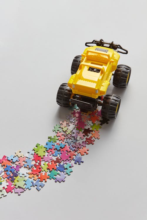 Yellow Toy Truck Running Over Puzzle Pieces