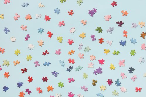 Free Scattered colorful puzzle pieces on a light blue background offer a vibrant and playful composition. Stock Photo