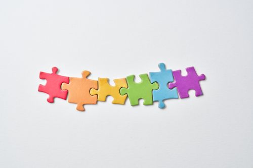 Free Colorful puzzle pieces aligned on a white background, showcasing rainbow hues and minimalistic design. Stock Photo