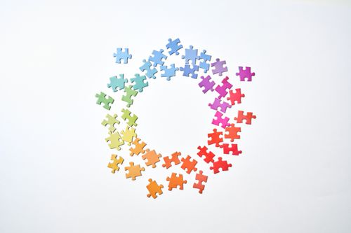 Free A circle formed by rainbow-colored puzzle pieces on a white background symbolizing unity and diversity. Stock Photo
