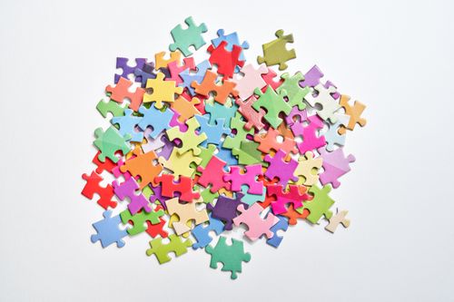 Free A vibrant collection of colorful puzzle pieces scattered on a clean white background, perfect for creativity themes. Stock Photo