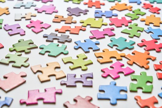 Vibrant jigsaw puzzle pieces scattered on a white background in a still life composition.