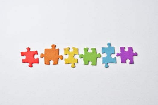 Vibrant row of multicolored puzzle pieces laid out on a white surface.
