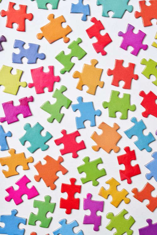 Free A vibrant collection of colorful jigsaw puzzle pieces scattered on a white background. Stock Photo