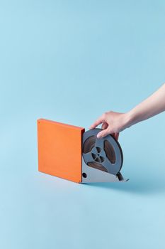 Close-up of a vintage film reel being held, highlighting analog nostalgia against a blue background.