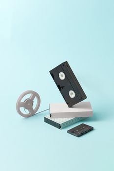 Vintage VHS and cassette tape styled on a pastel blue backdrop capturing nostalgia.