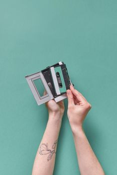 A pair of hands holding a vintage cassette player against a pastel background. Retro vibes.