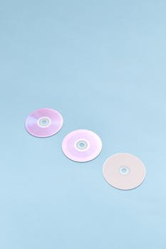Minimalist image of three CDs on a light blue background with copy space.