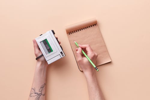 Person Holding Cassette Player and a Pencil