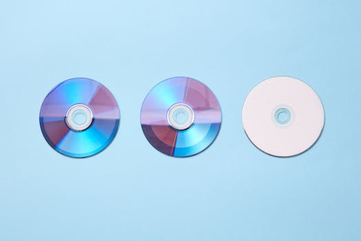 Three classic compact discs with a nostalgic tone on a pastel blue background.