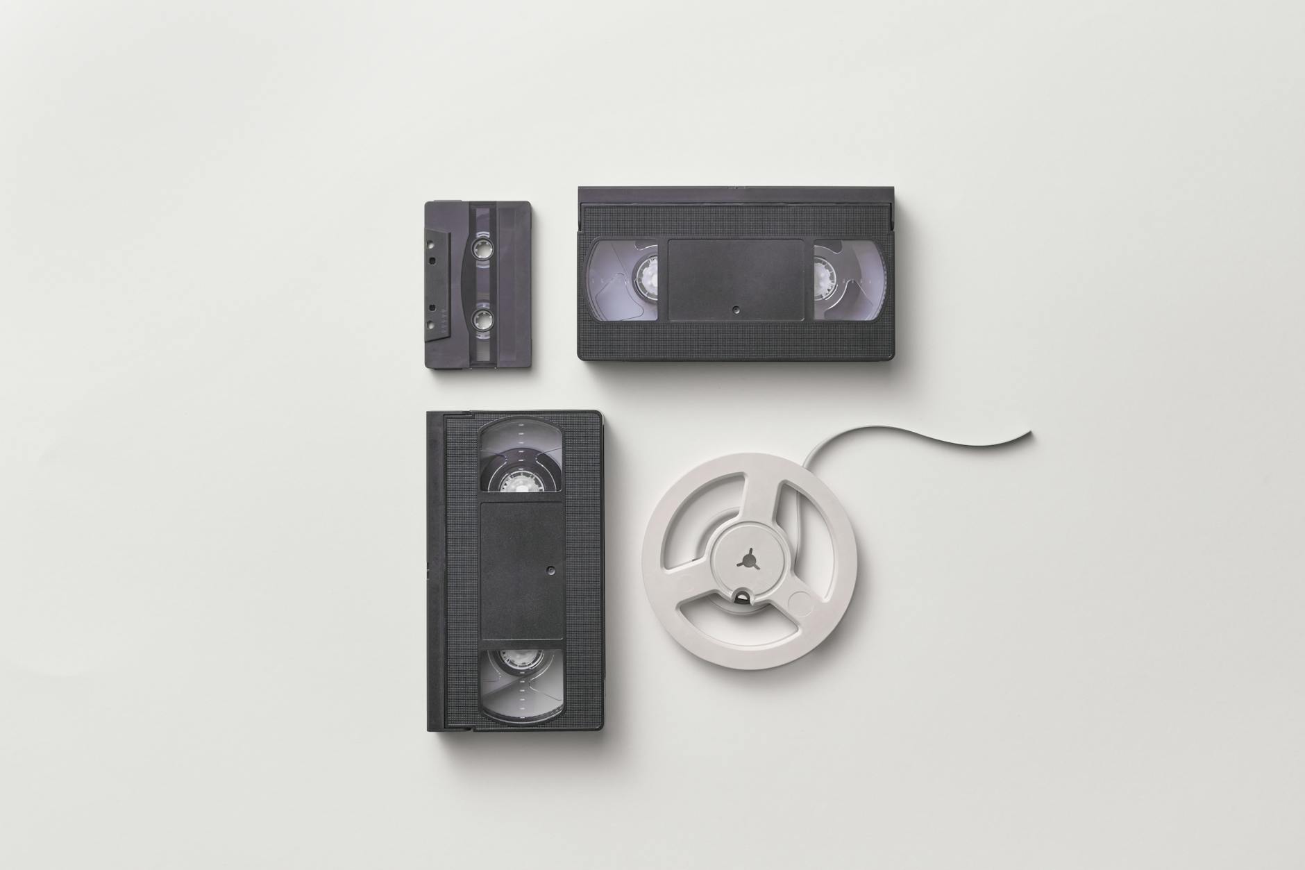 Collection of vintage audio and video tapes including VHS and cassette on a white background.