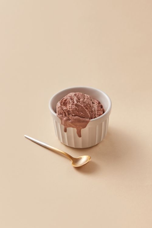 Free Creamy chocolate ice cream in a cup with a golden teaspoon on beige background. Stock Photo