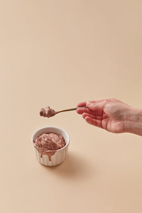 A Person Holding Holding a Teaspoon of Ice Cream
