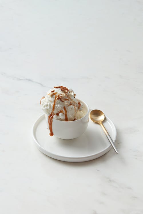A Vanilla Ice Cream with Chocolate Syrup  in White Ceramic Cup with Saucer